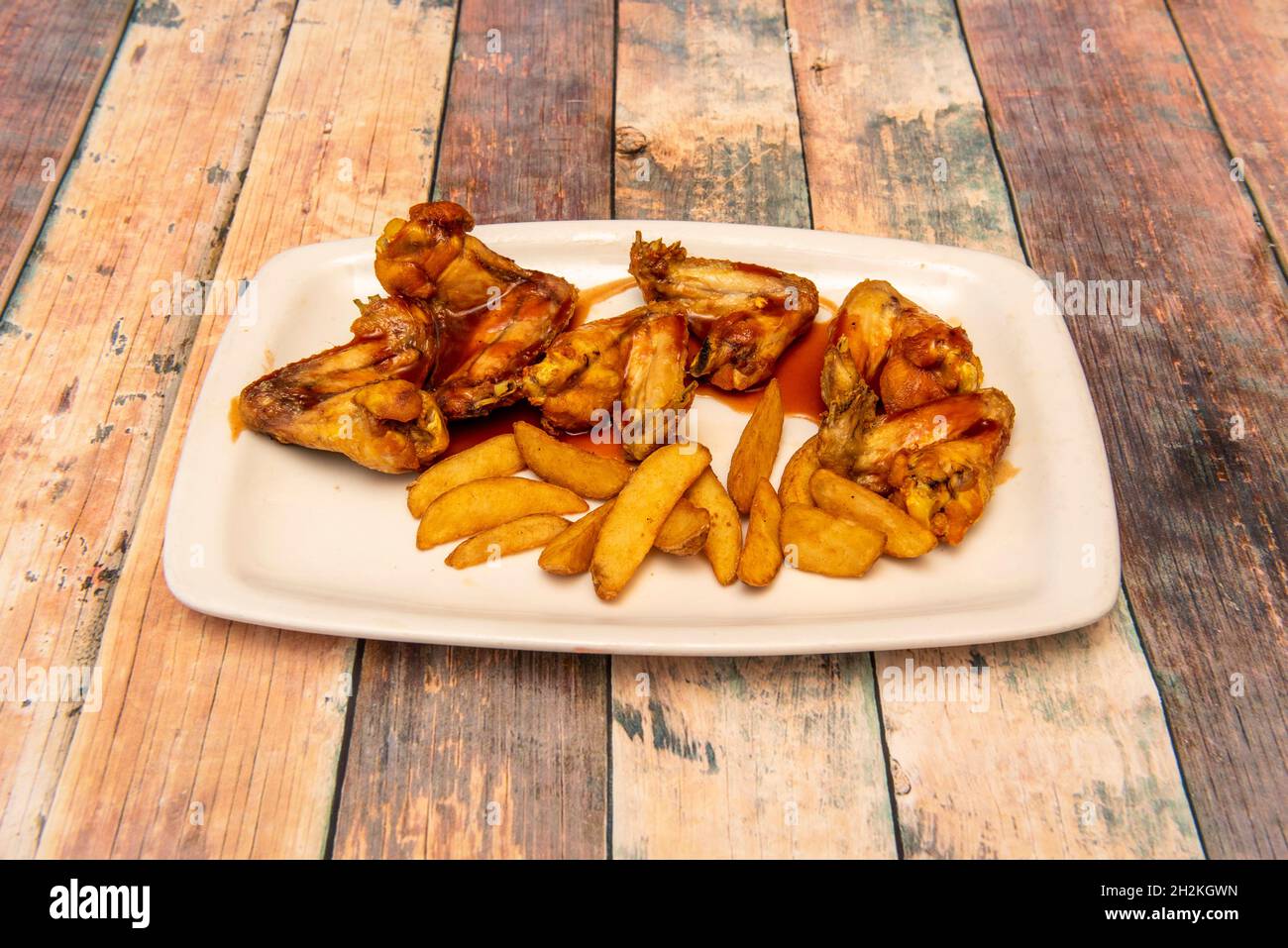 Delicious serving of fried chicken wings with barbecue sauce and French