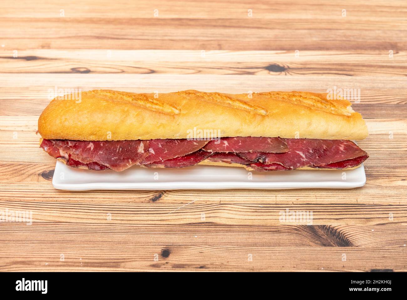 Great Spanish sandwich of smoked beef jerky sausage on white plate