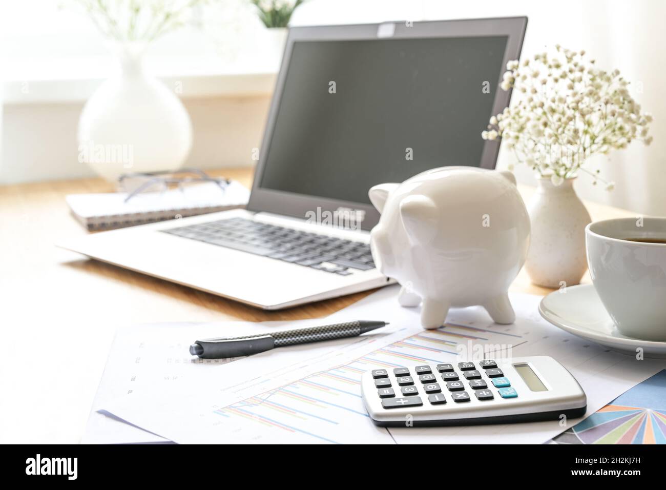 Finance accounting on a desk with laptop computer, calculator, piggy ...