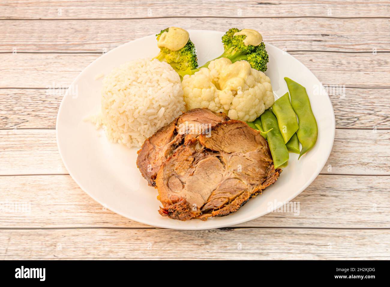 Menu plate with baked pork accompanied by white rice, green beans, cauliflower and cooked broccoli Stock Photo