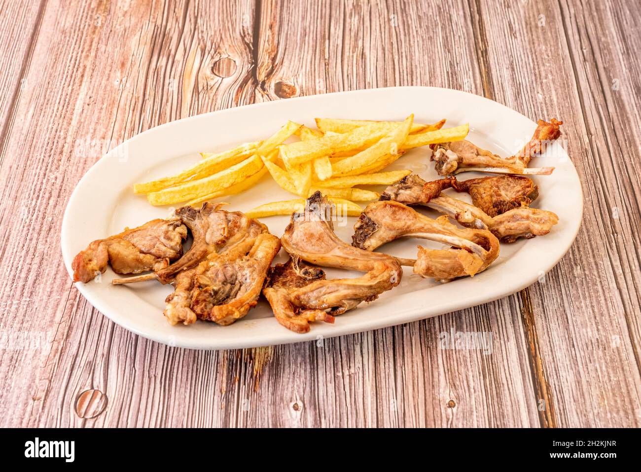 Tray of kid chops fried in olive oil with a garnish of homemade chips