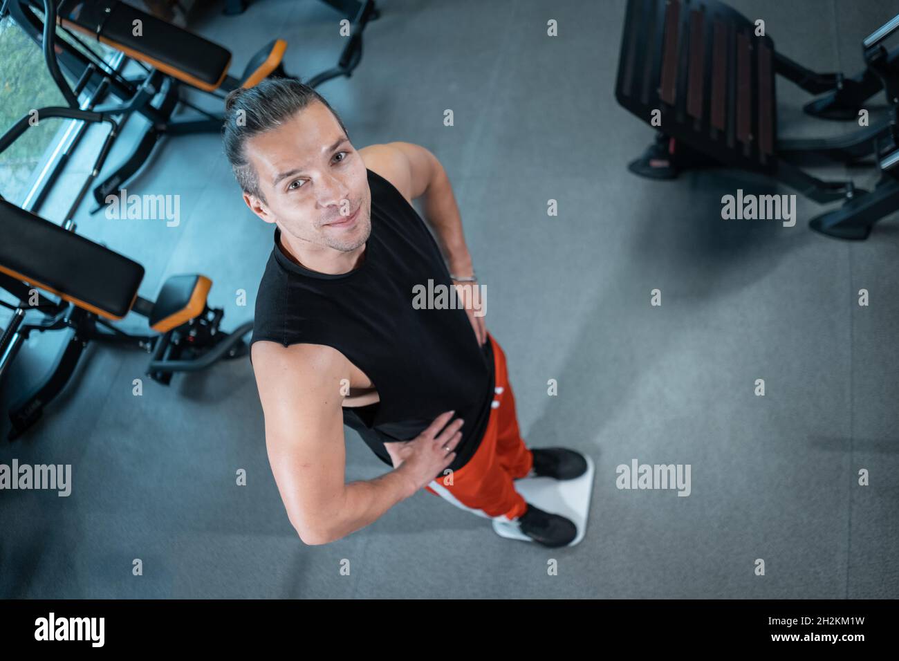 young attractive athlete male weight with scale in gym and dieting Stock Photo