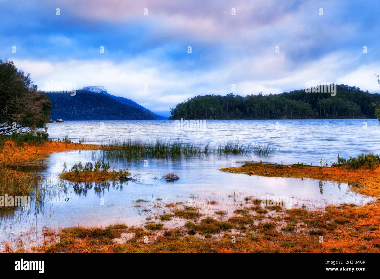Wed muddy shores of Lake St Clair around Platypus bay at sunrise in cloudy winter cold weather