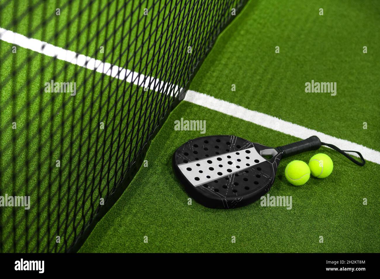 Closeup view of a paddle racket and balls in a padel tennis court near
