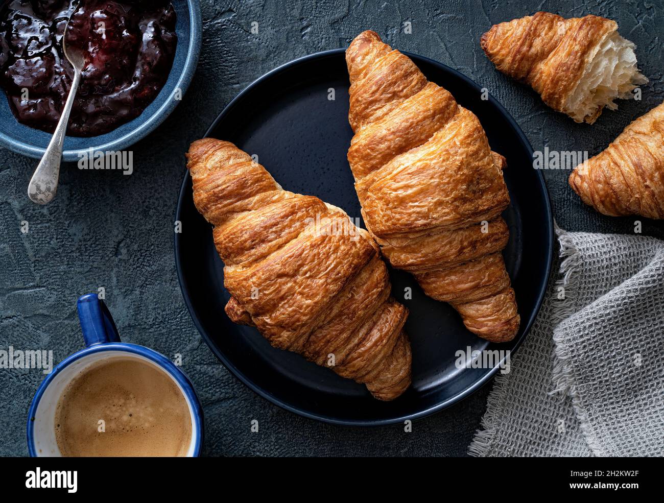 Delicious buttery croissants with jam and coffee on a blue background. Stock Photo