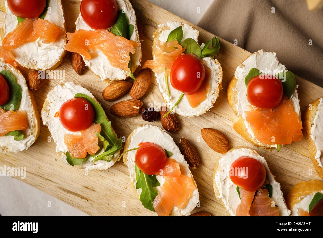 dry aged smoked salmon on the slices of bread and cream cheese sandwiches with cherry tomatoes and rocket salad top view Stock Photo