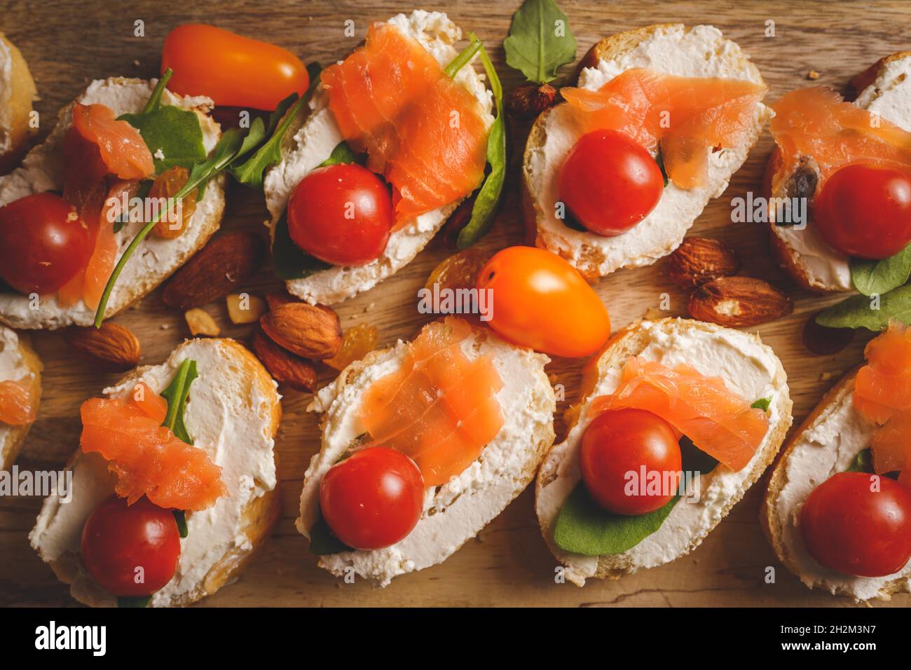 dry aged smoked salmon on the slices of bread and cream cheese sandwiches with cherry tomatoes and rocket salad Stock Photo