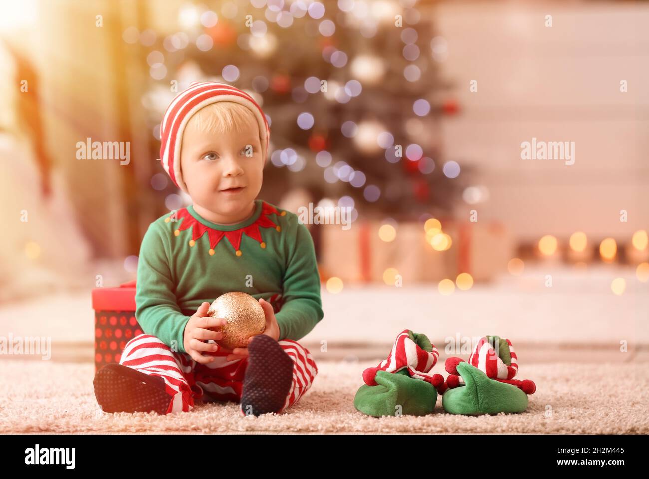 Cute little baby in elf's costume at home on Christmas eve Stock Photo