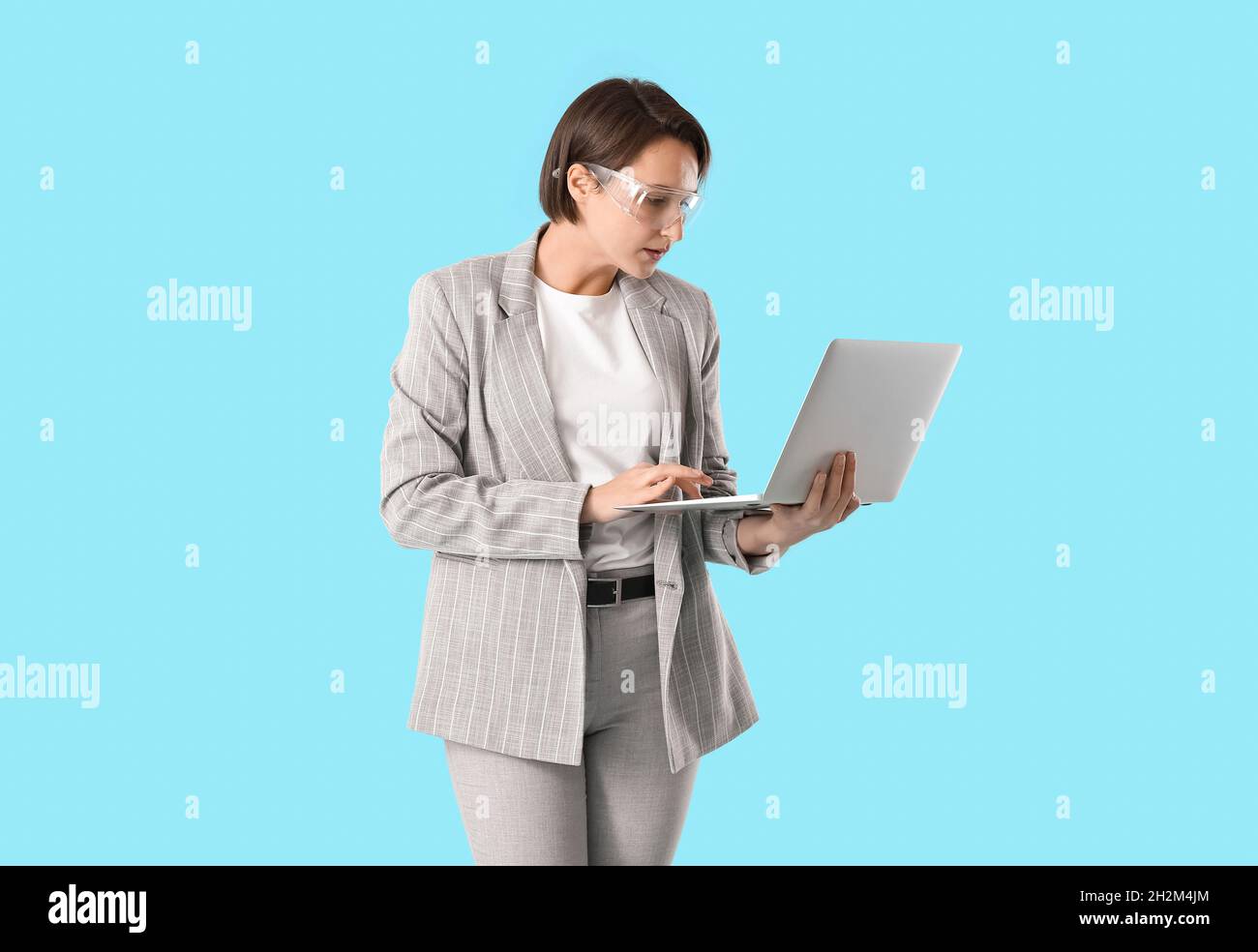 Female industrial engineer using laptop on blue background Stock Photo