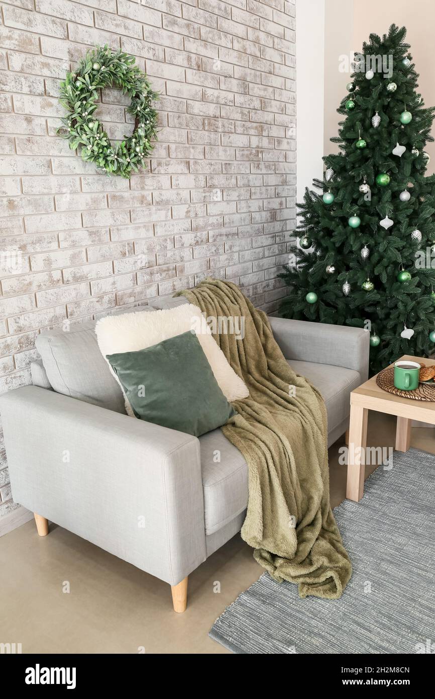 Interior of living room with Christmas tree, mistletoe wreath and sofa