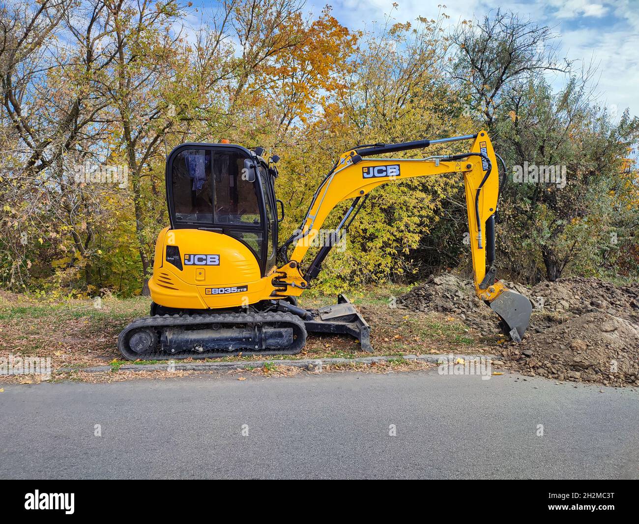 Modern yellow JCB digger or excavator performs excavation work outdoors Stock Photo