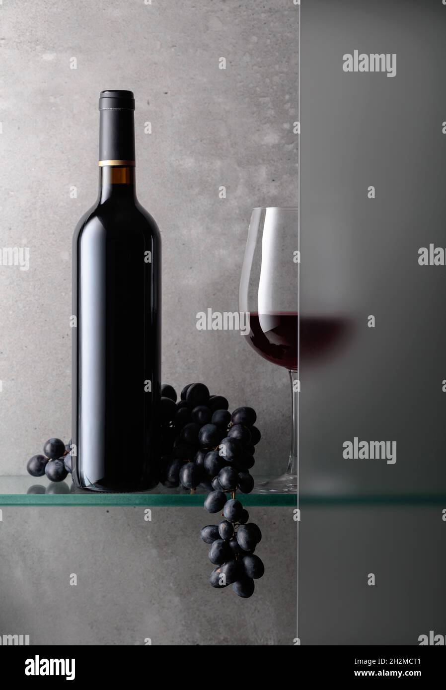 Bottle and a glass of red wine with a bunch of grapes. The still life ...