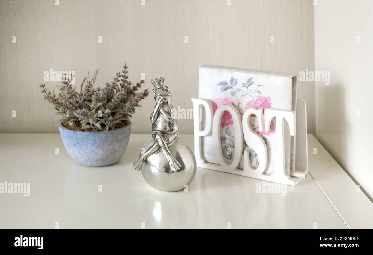 Purple lavender flowers in a blue flower pot, frog figurine and napkin holder on a white table. Stock Photo