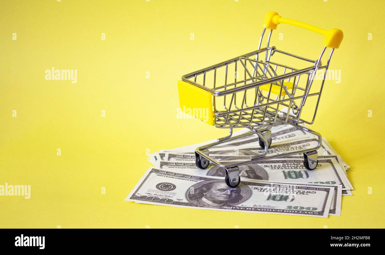 On a yellow background a grocery basket and dollars Stock Photo