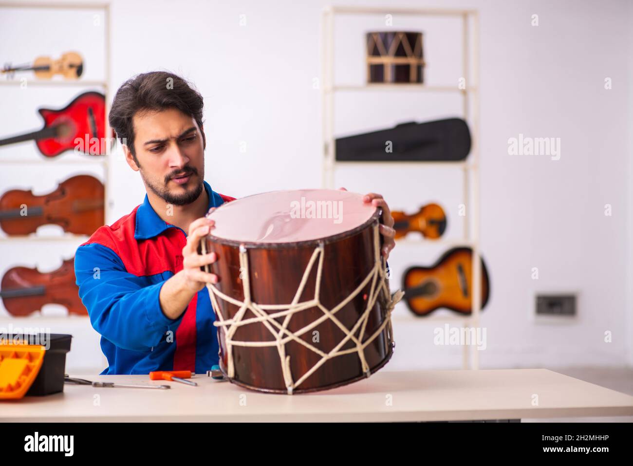 Young repairman repairing musical instruments at workplace Stock Photo