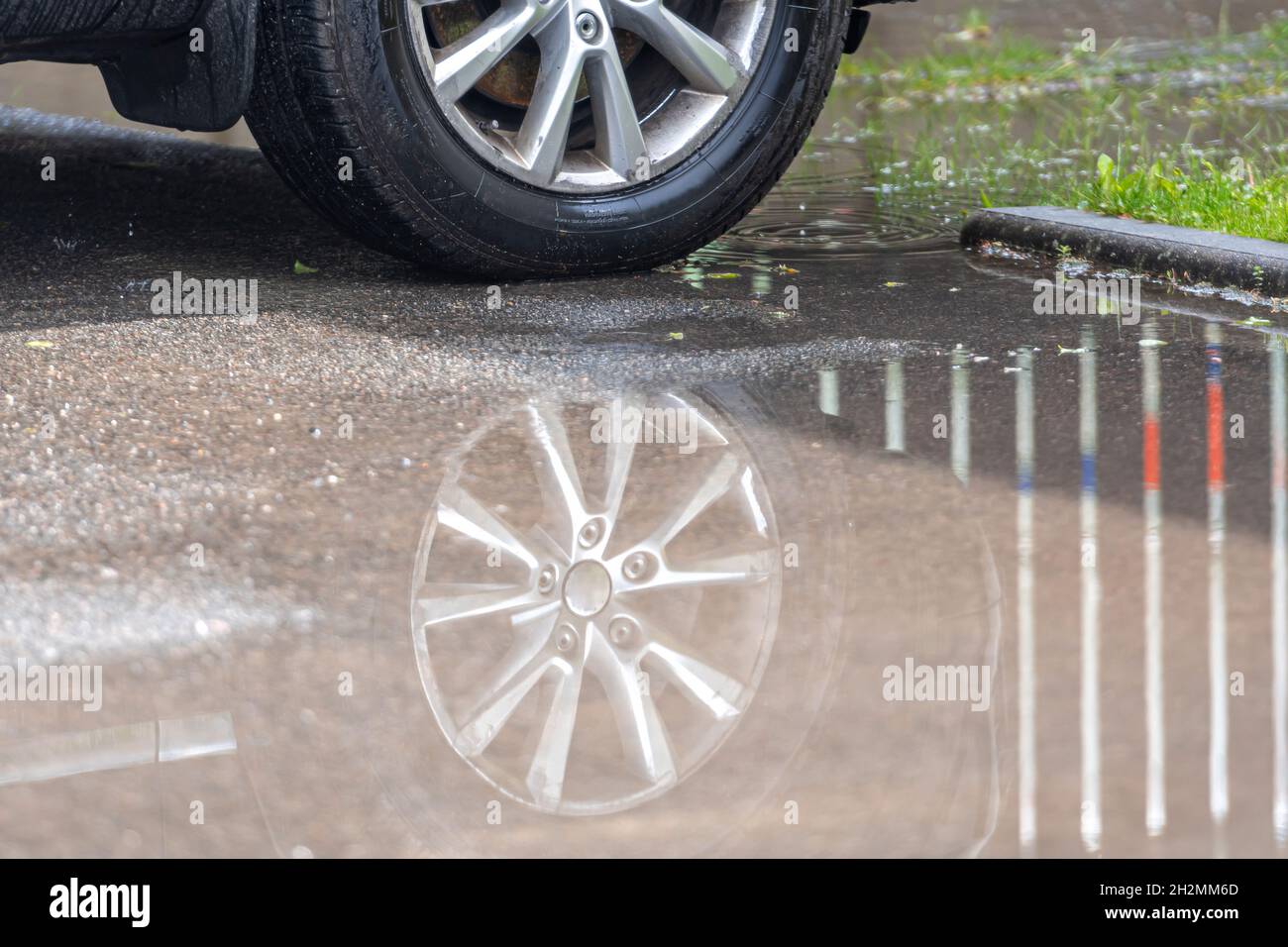 puddle on the pavement with a reflection of the car wheel, close-up ...