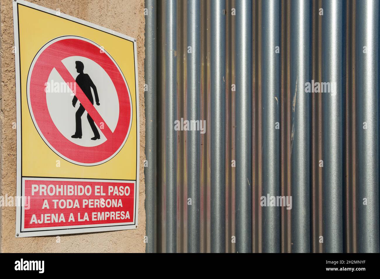 Closeup of a no trespassing sign, written in Spanish, next to a metal
