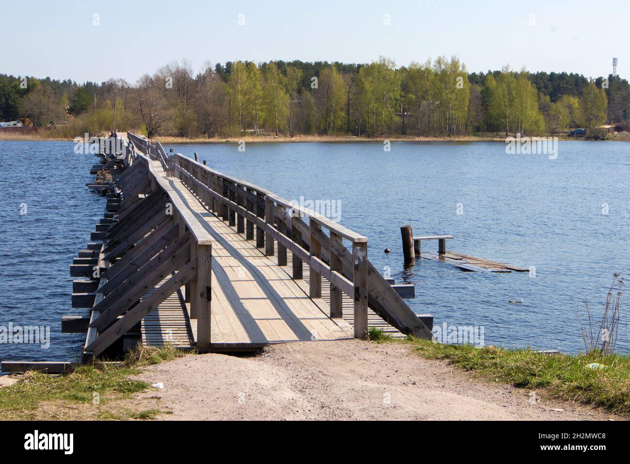 Old wooden vintage half destroyed pedestrian bridge with handrail over the lake Stock Photo