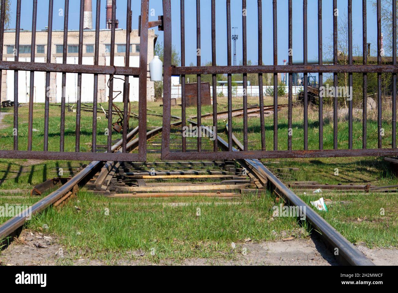 Old abandoned railroad track going into perspective behind a rusty gate Stock Photo