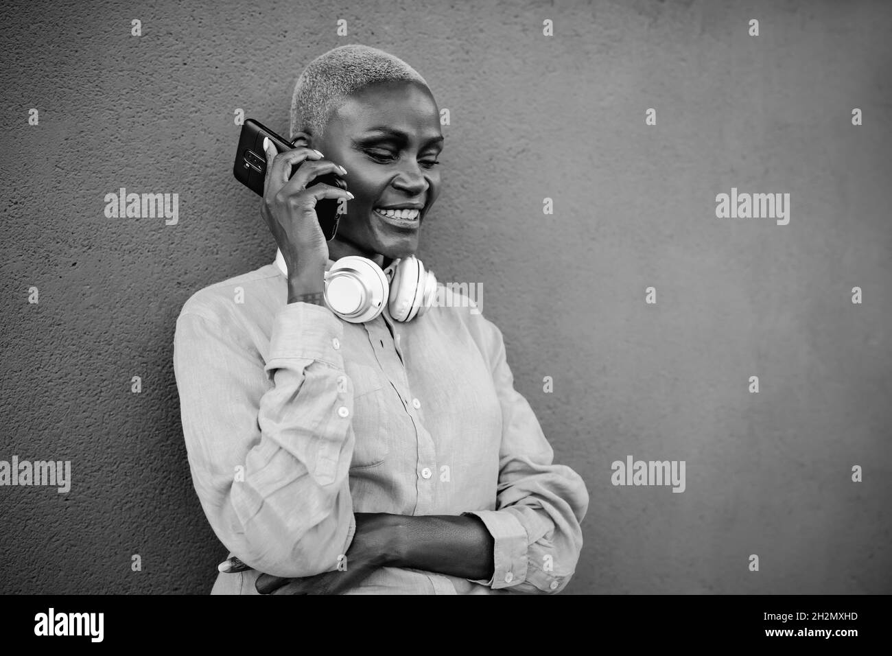Happy smiling African woman doing a call with mobile smartphone outdoor - Black and white editing Stock Photo