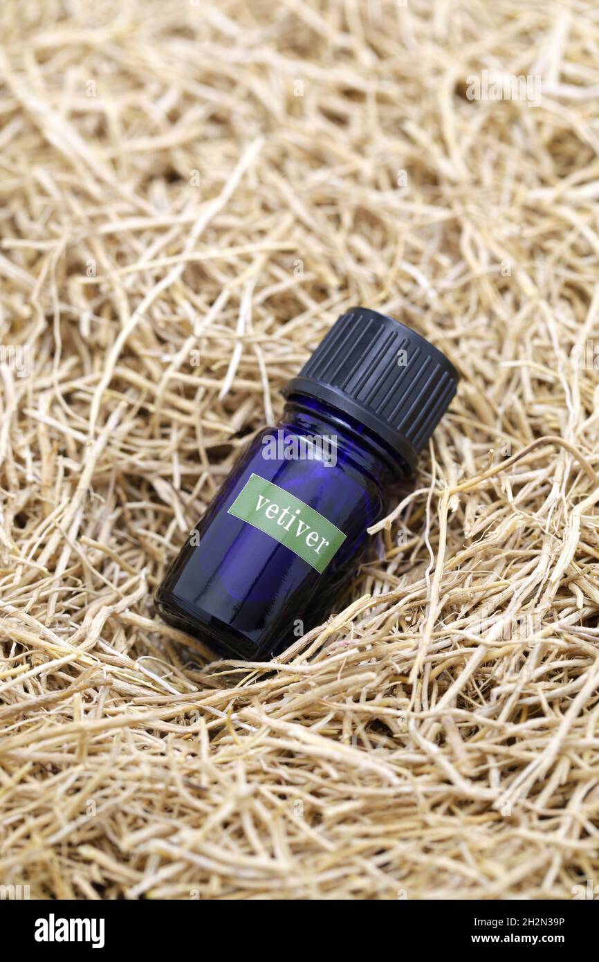 dried vetiver roots and vetiver essential oil in a glass vial