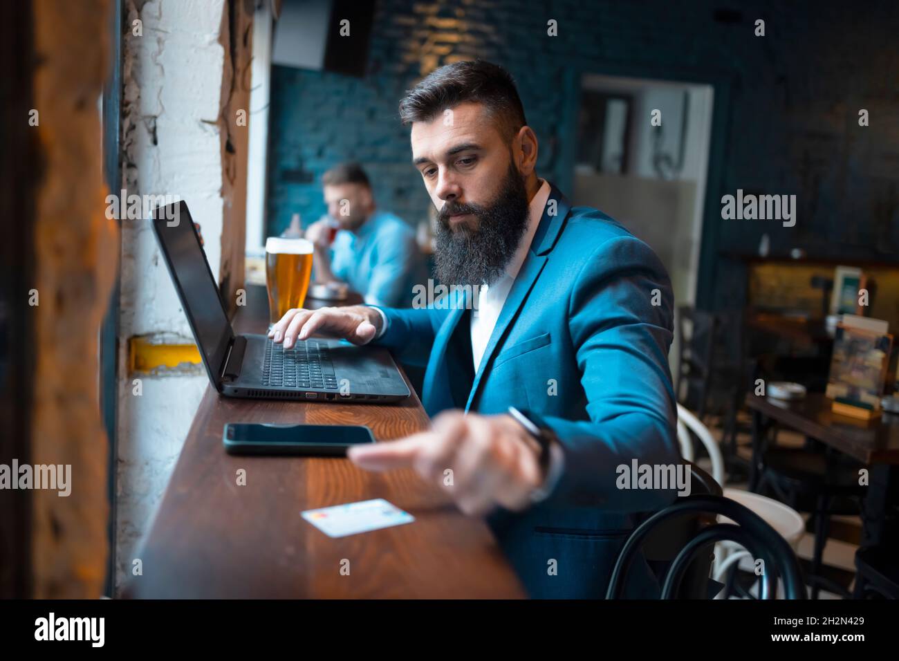 Young businessman using a laptop and a credit card in a cafe Stock Photo