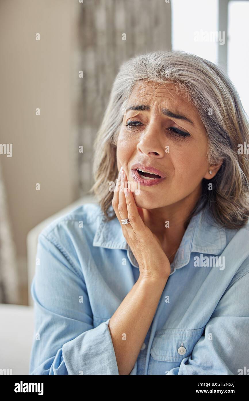 Mature Woman At Home Suffering From Pain With Toothache Stock Photo