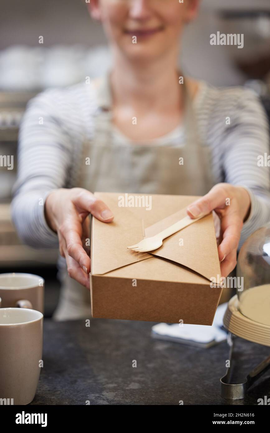 Close Up Of Female Worker in Cafe Serving Meal In Sustainable Recyclable Packaging With Wooden Fork Stock Photo