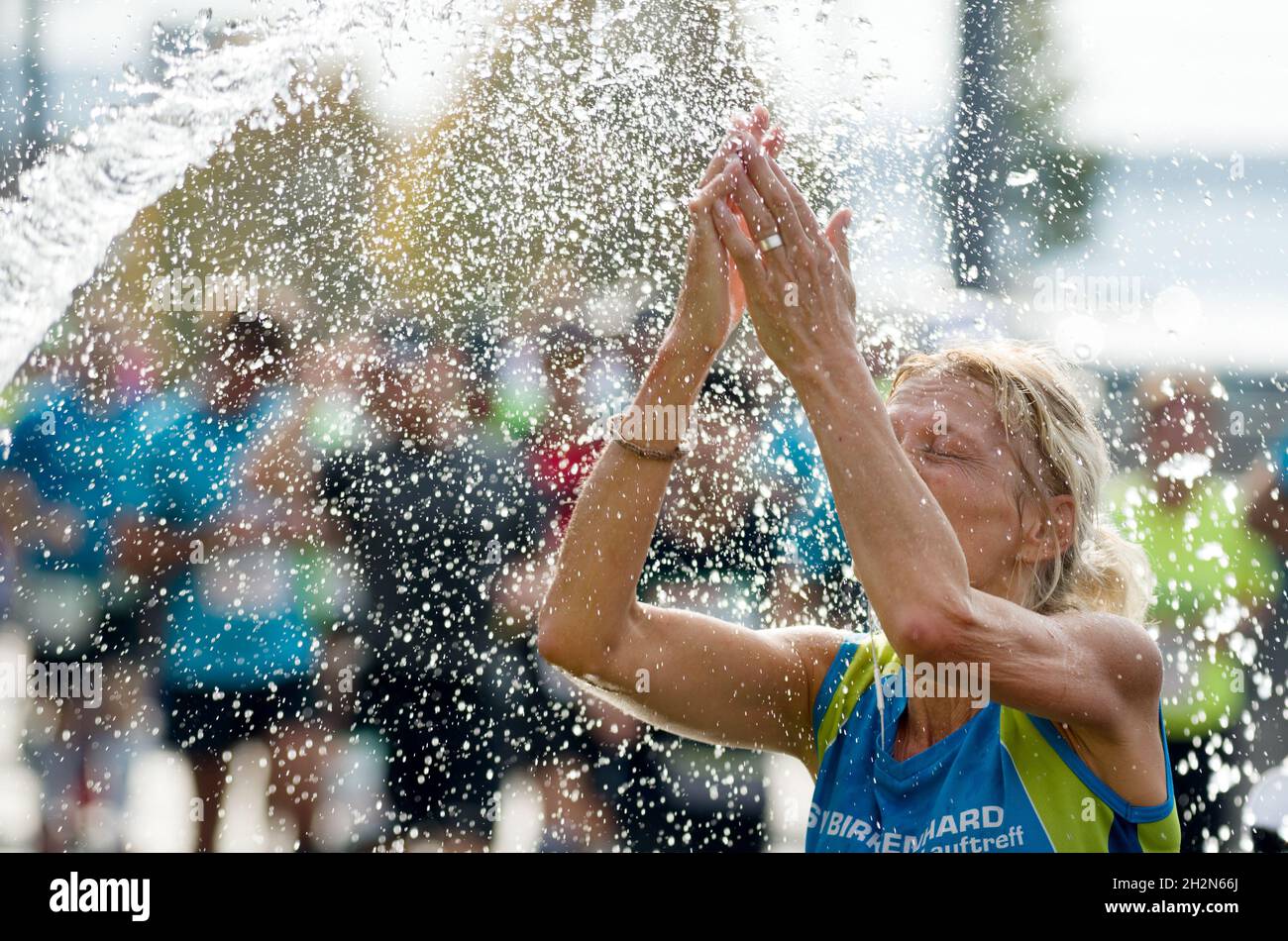 Female senior marathon runner stands in a water sprinkling. October 2018, Budapest Stock Photo