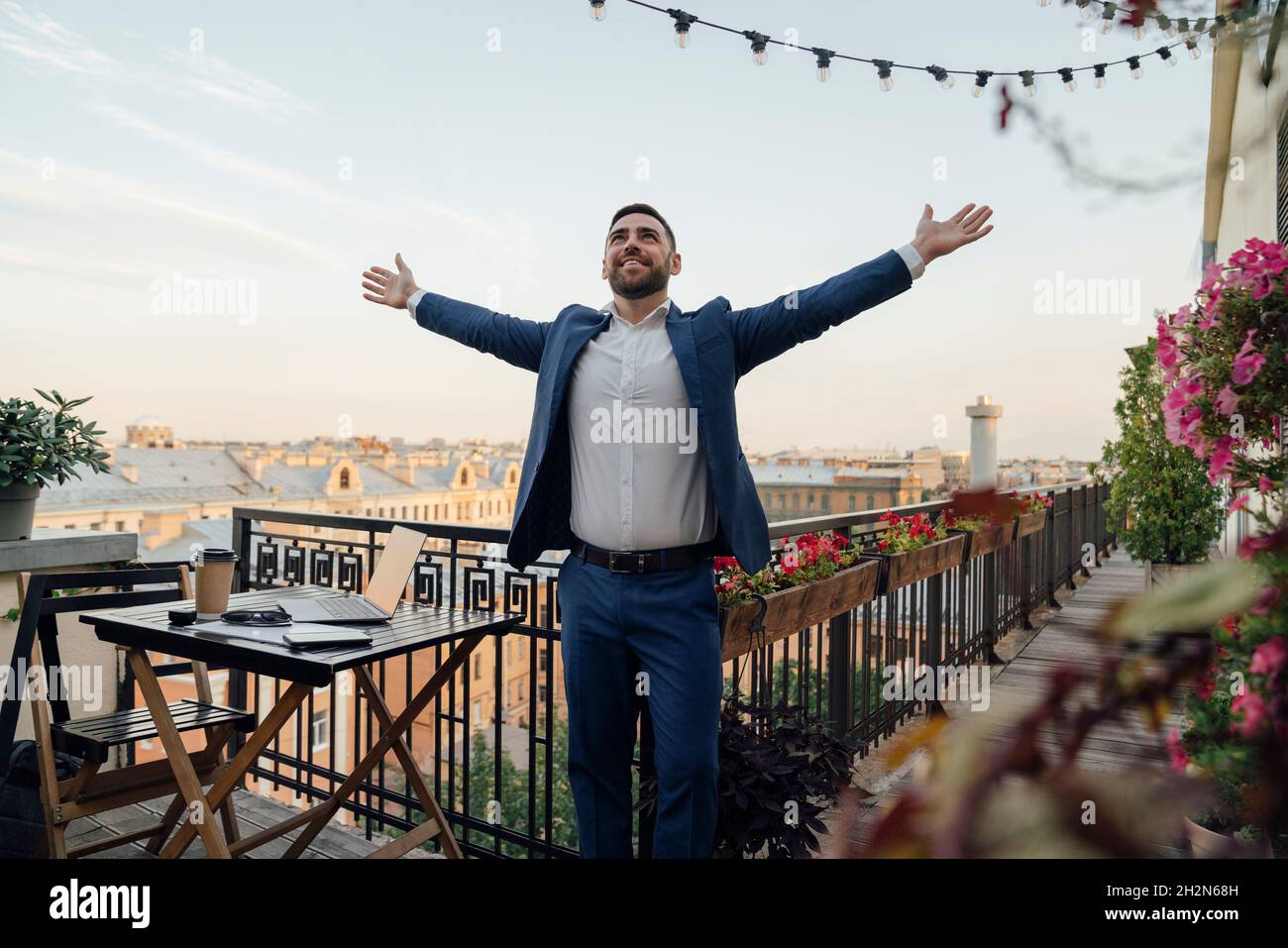 Male business person with arms outstretched standing in office balcony Stock Photo