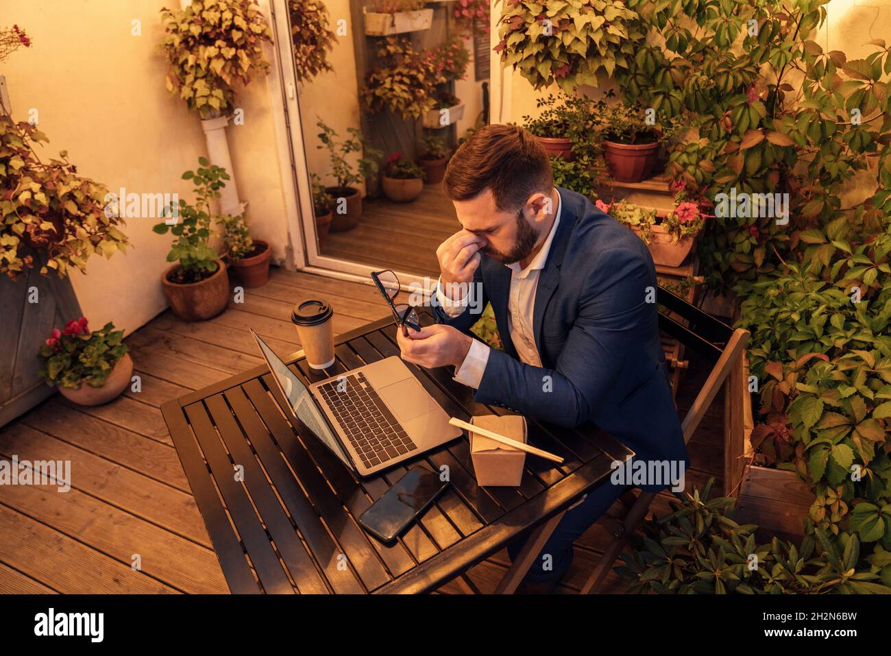 Exhausted businessman holding eyeglasses while working late in office balcony Stock Photo