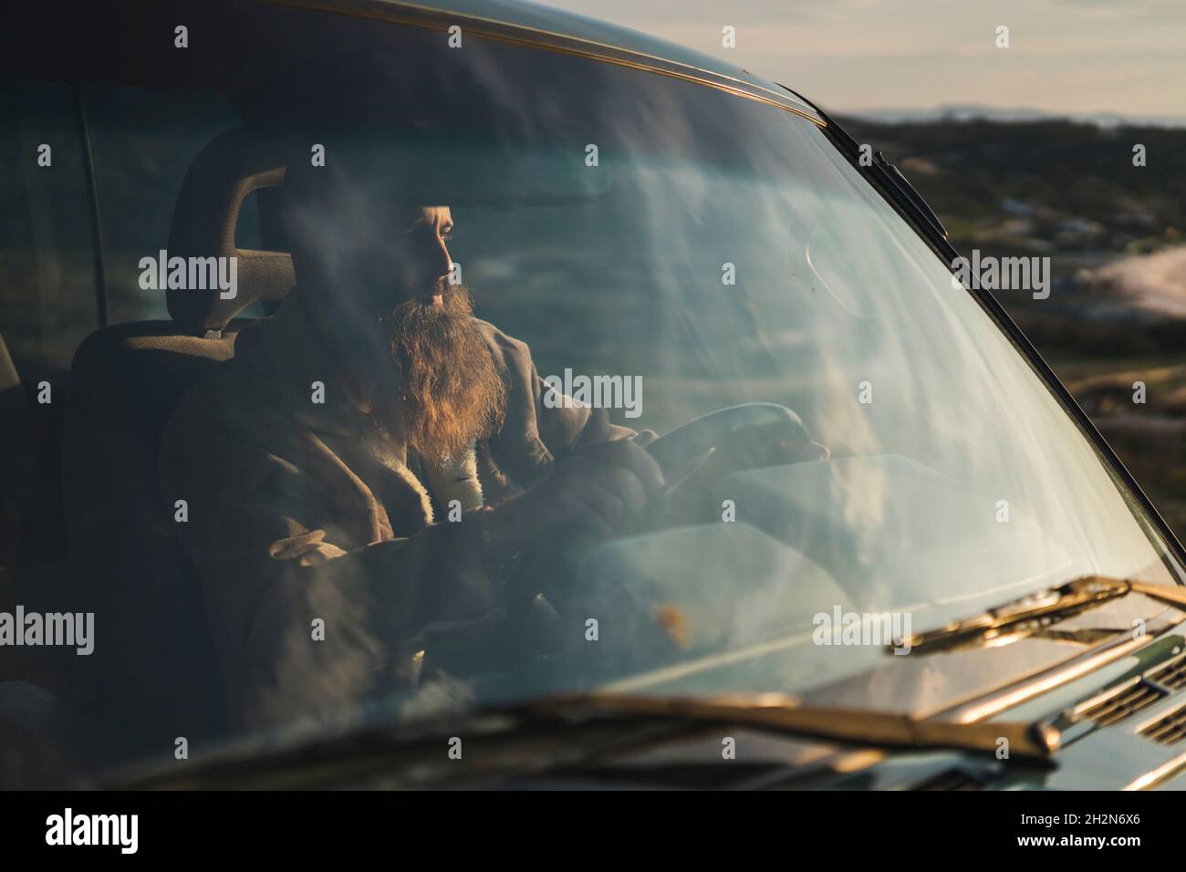 Young man driving car during sunset Stock Photo