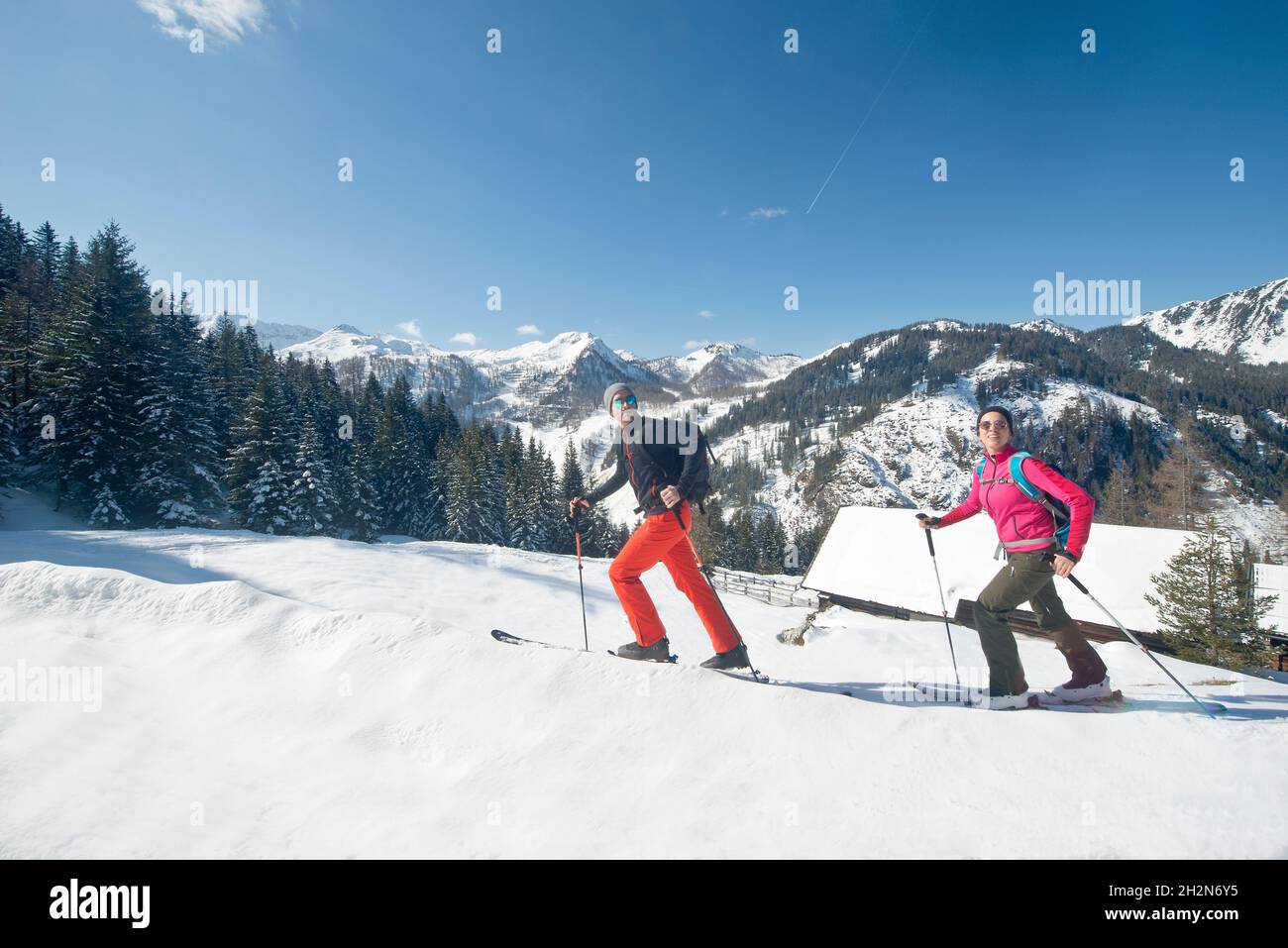 Smiling young couple enjoying ski touring during vacation Stock Photo