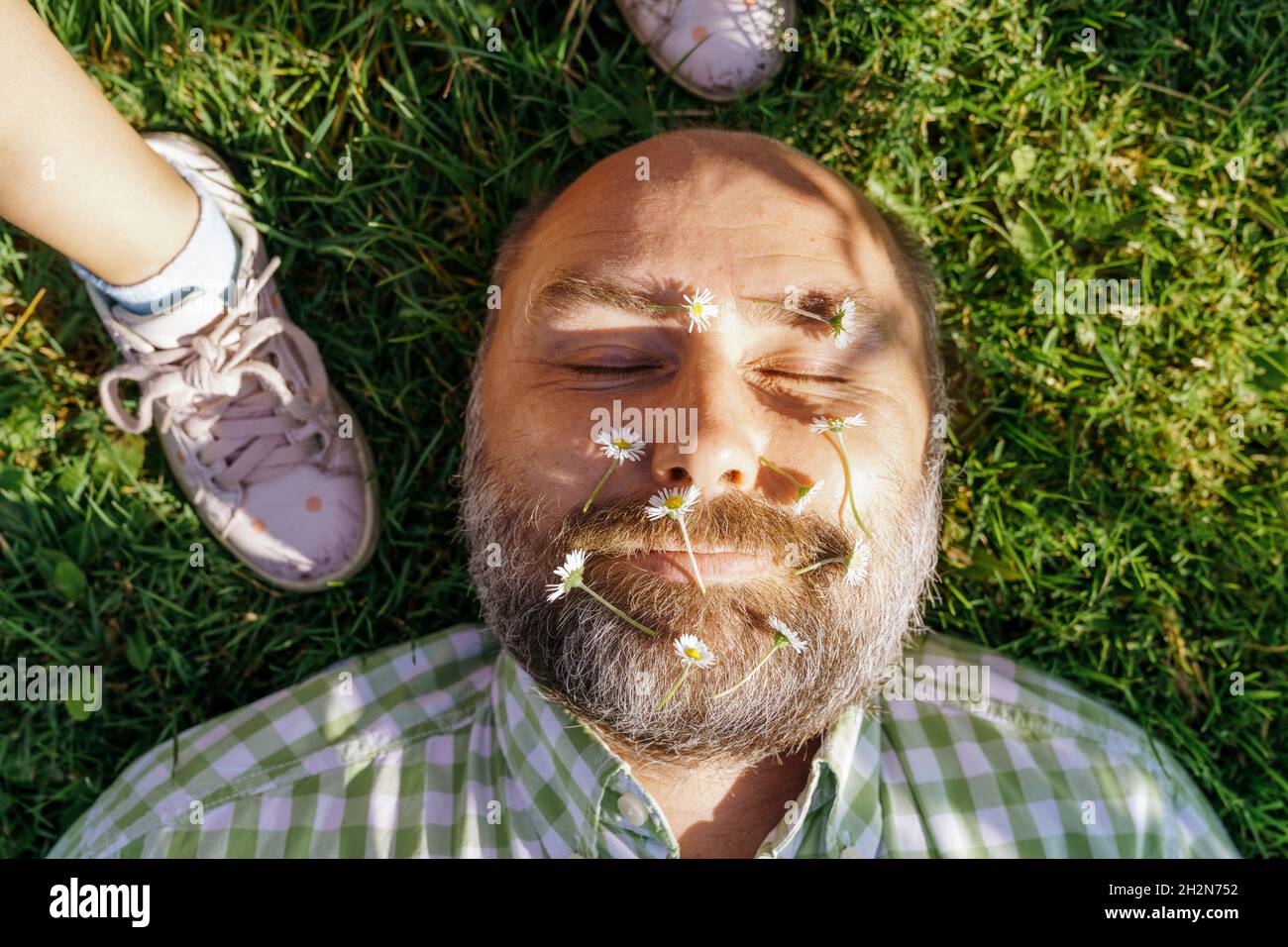 Man with flowers on face lying on grass by daughter Stock Photo Alamy