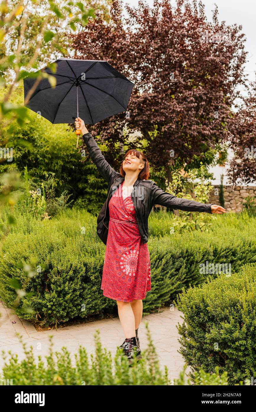 Woman with umbrella enjoying rainy day at park Stock Photo - Alamy