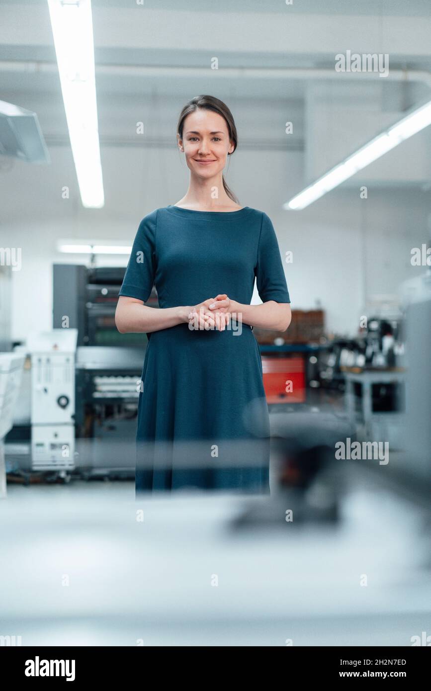 Female professional with hands clasped standing in workshop Stock Photo