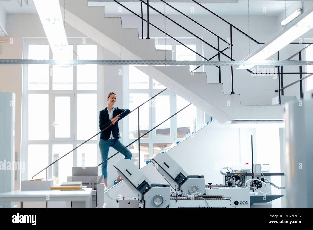 Leaning Railing Female business professional leaning on railing in workshop Stock Photo ...
