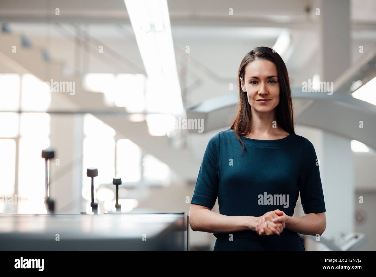 Businesswoman with hands clasped standing in workshop Stock Photo