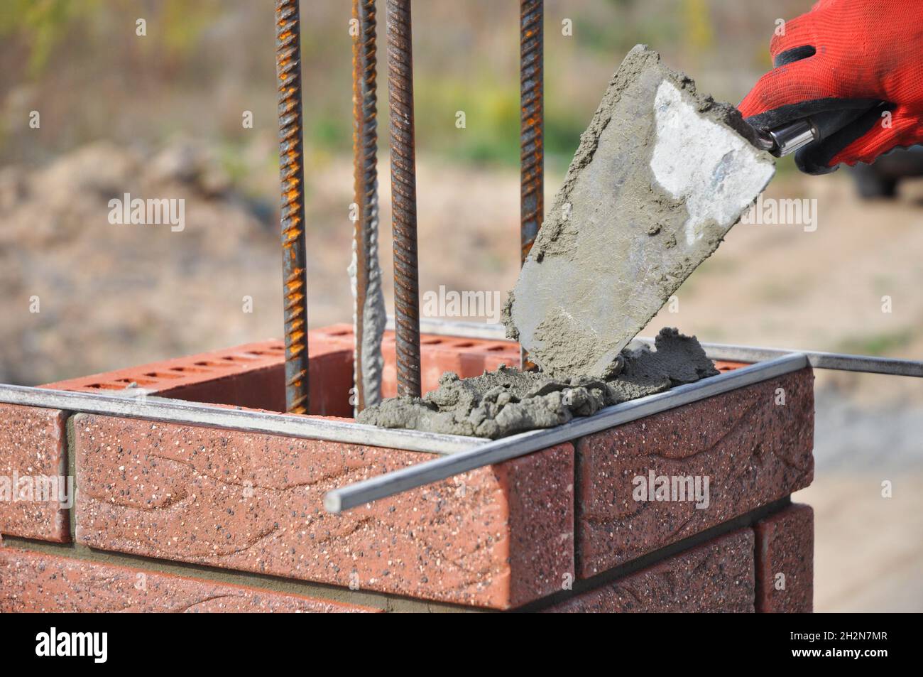 Bricklayer Worker Installing Red Clinker Blocks and Caulking Brick
