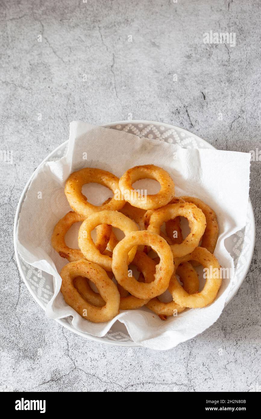 Battered onion rings in a dish, with paper towel to absorb grease and