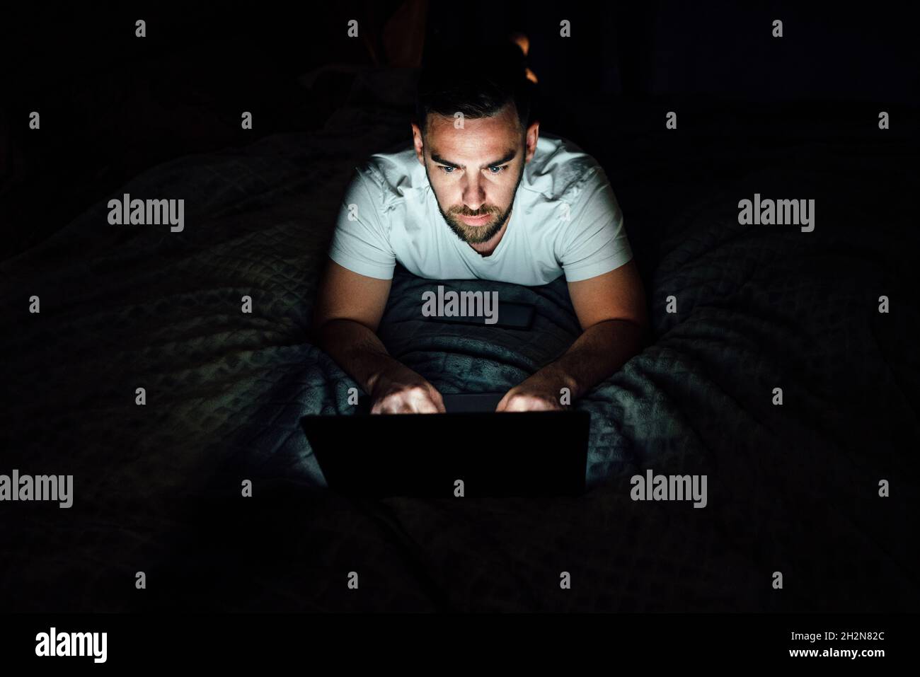 Serious man using laptop in bedroom Stock Photo