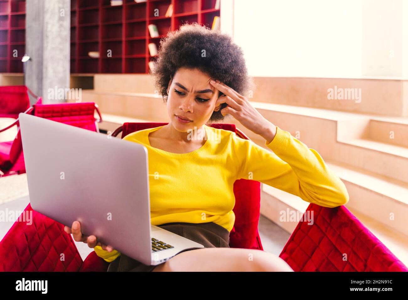 Worried businesswoman looking at laptop while sitting in office Stock Photo