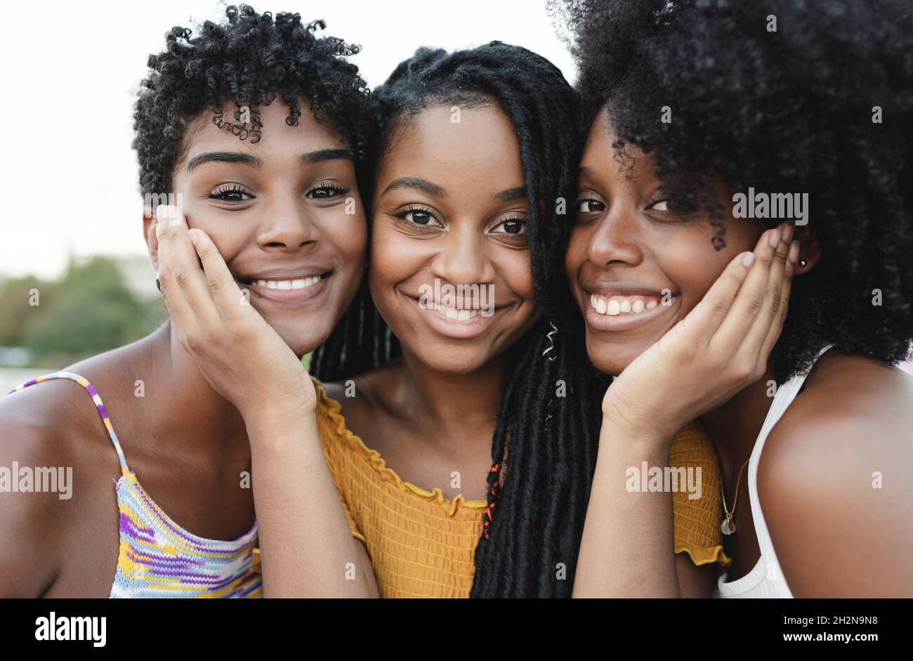 Smiling young female friends with cheek to cheek Stock Photo - Alamy