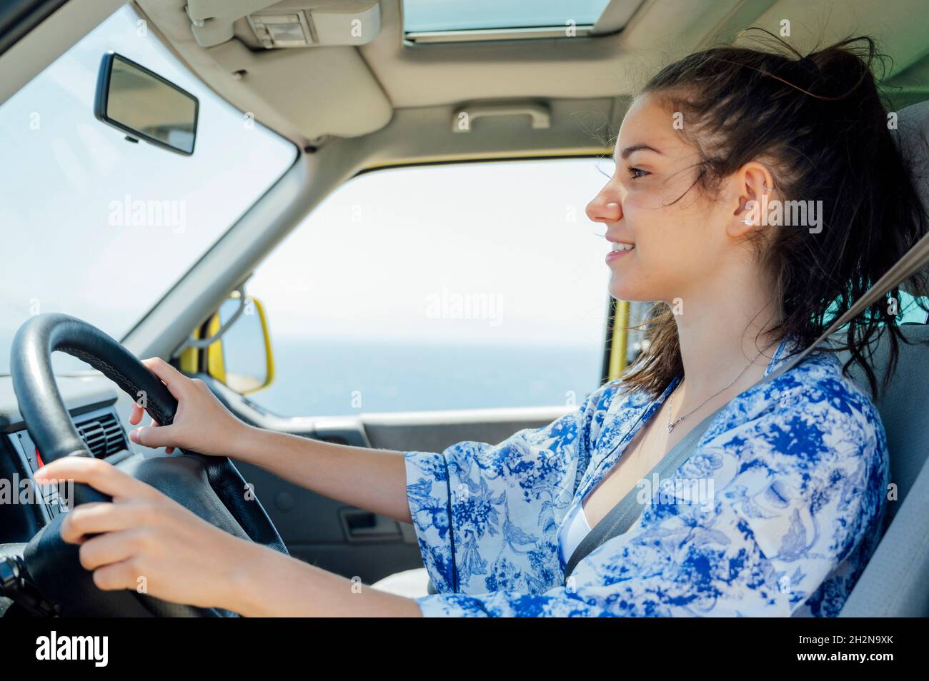 Smiling woman driving camper van during vacation Stock Photo