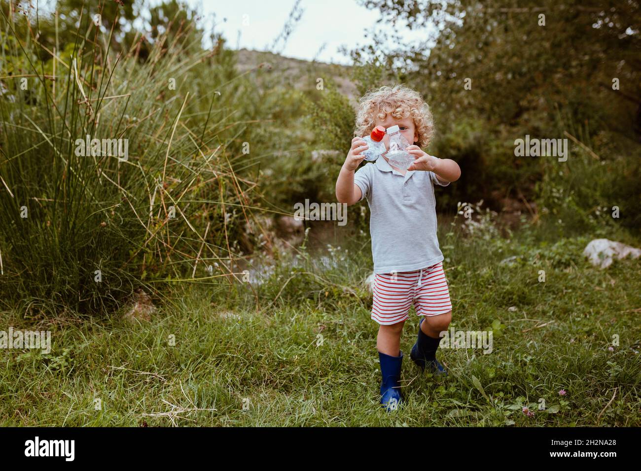 Boy collecting plastics on meadow Stock Photo Alamy
