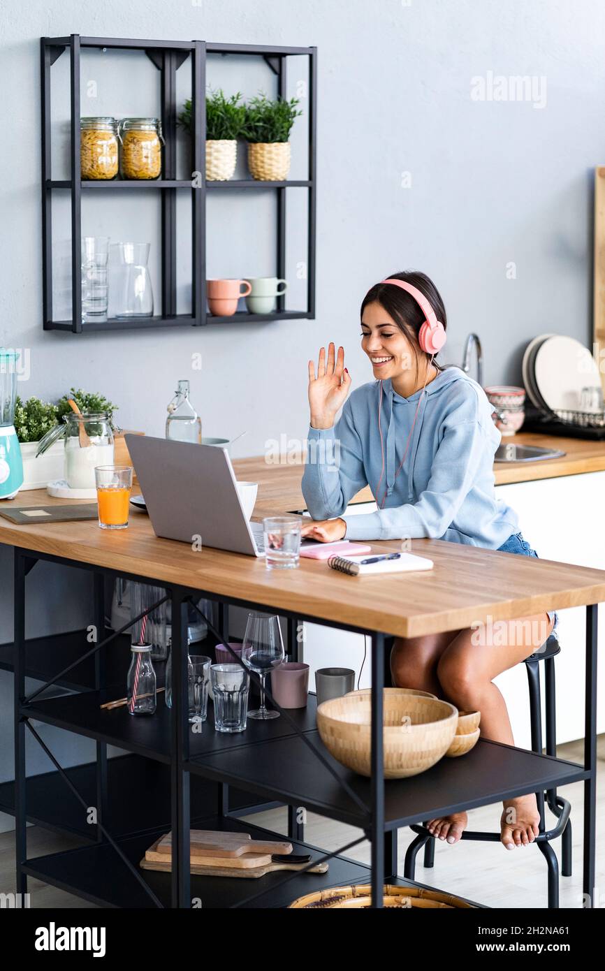 Woman using laptop while sitting at kitchen counter Stock Photo