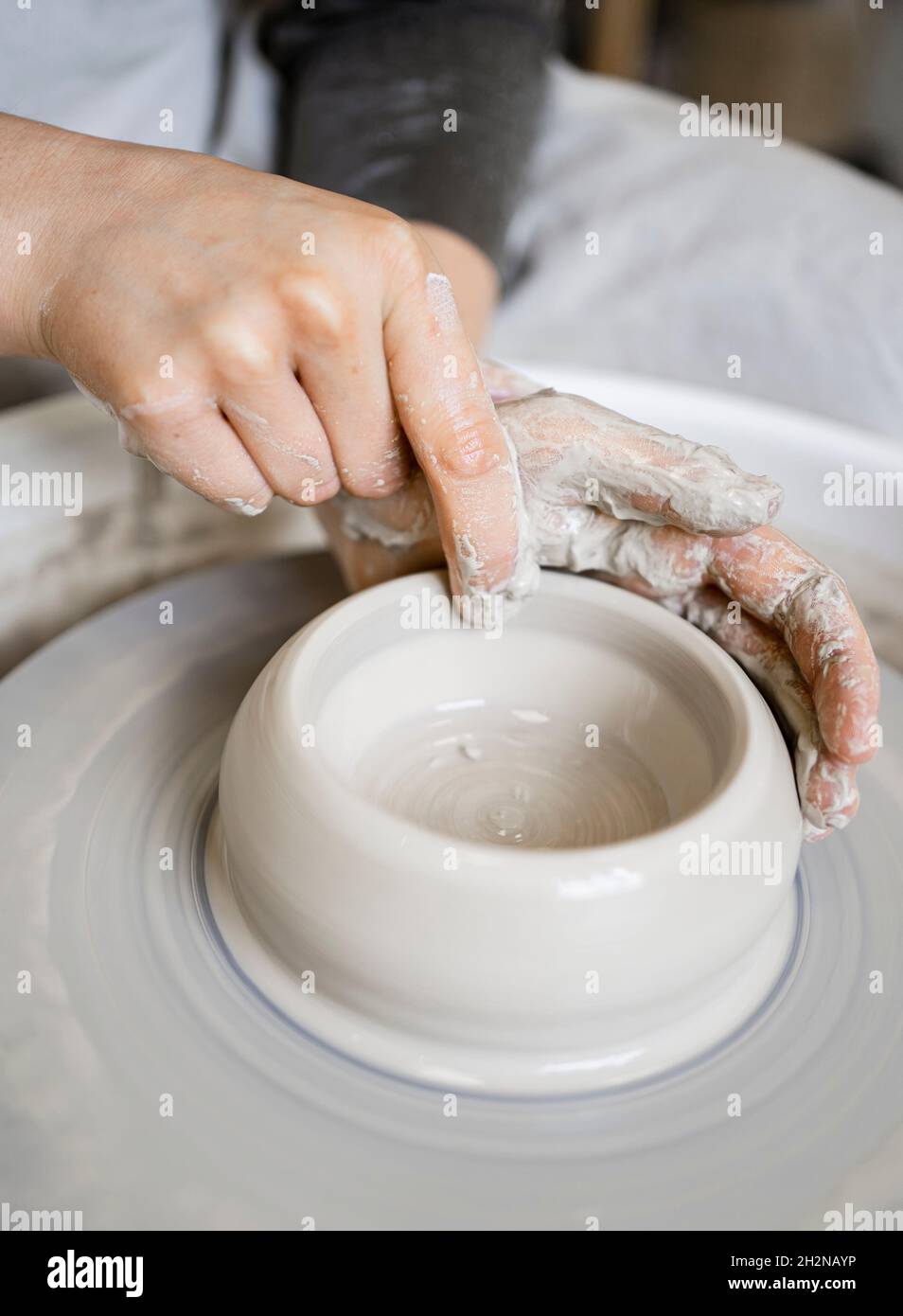 Young craftswoman molding clay with finger on pottery wheel Stock Photo