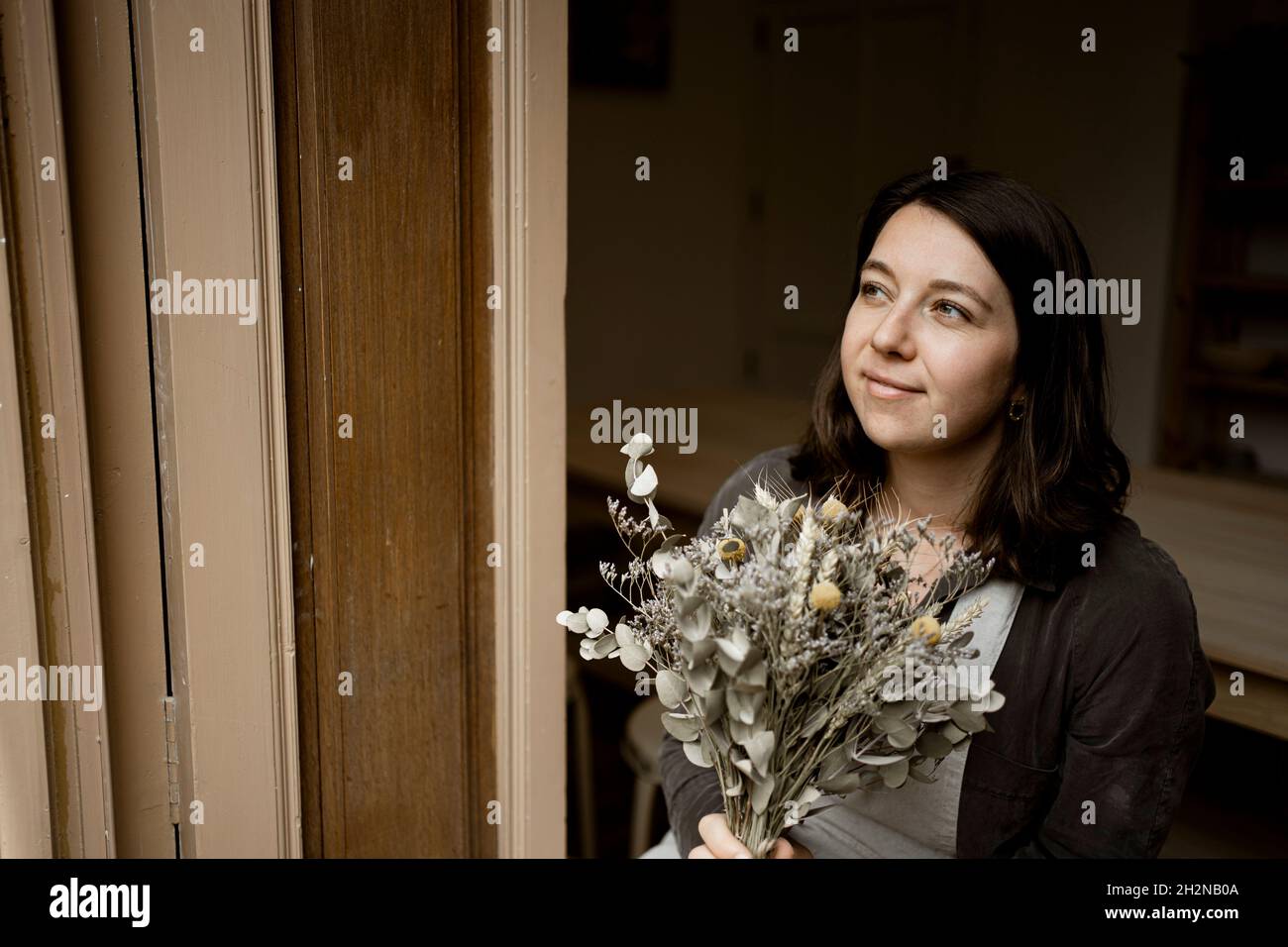 Thoughtful craftswoman with bouquet in workshop Stock Photo
