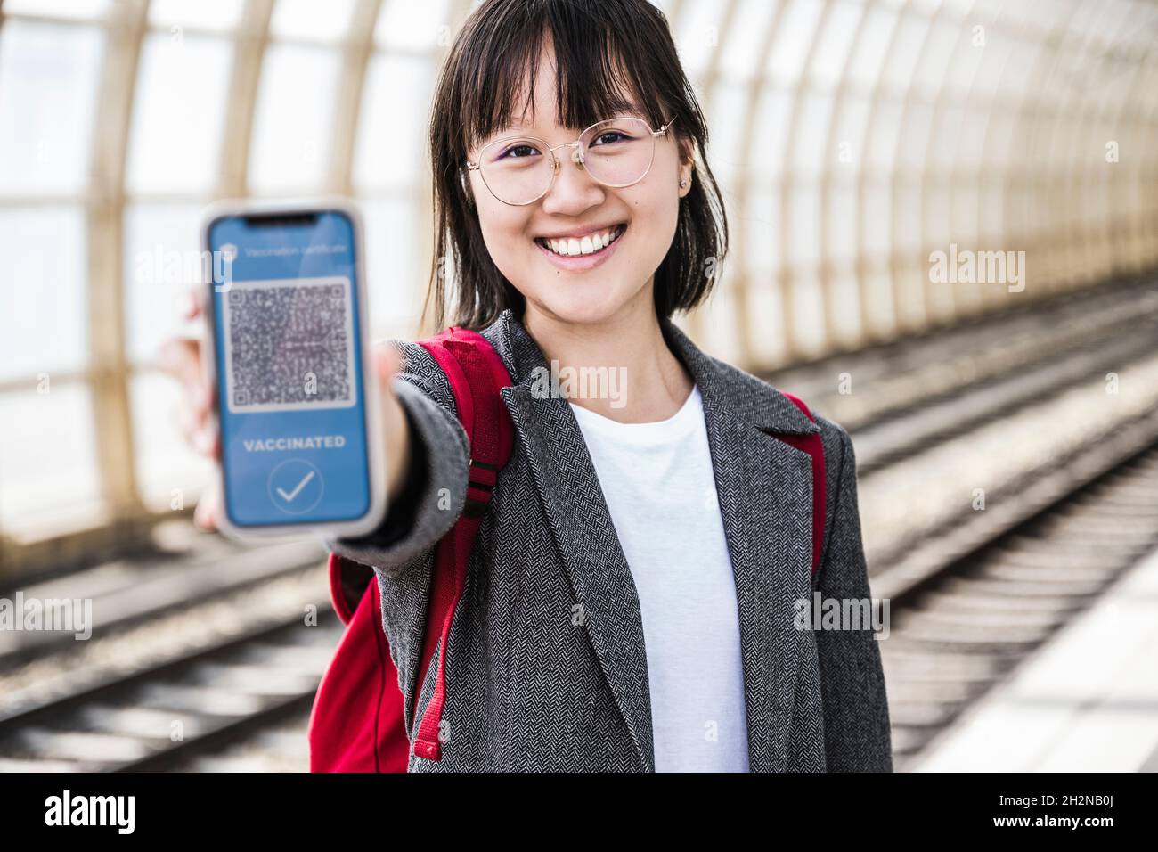 Teenage girl showing vaccination certificate on mobile phone screen at ...