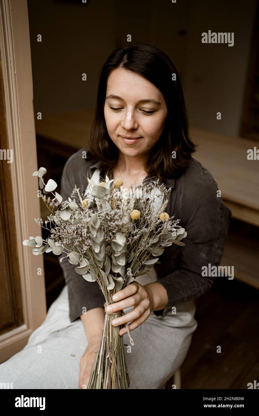 Smiling Craftswoman holding bouquet in workshop Stock Photo